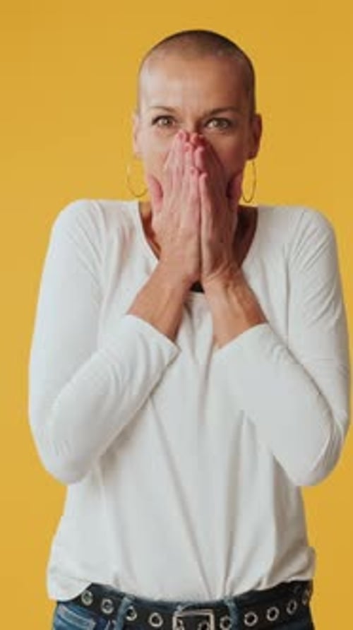 Surprised woman clapping her hands looking at camera isolated on yellow background in studio