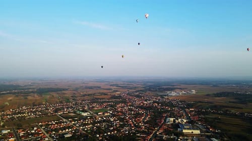 Stunning 4K aerial footage of a drone filming hot air balloons. Flying over farming fields and river