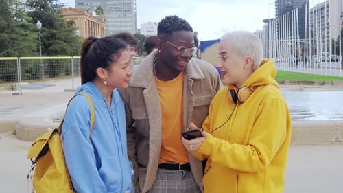 Group of Young Diverse Students in a City Browsing the Internet on Mobile Phone Having Fun