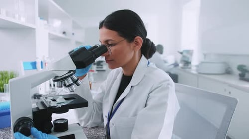 Female Scientist Using Microscope in Bright Laboratory