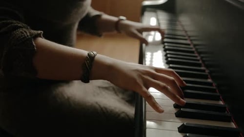 Cinematic close-up shot of a woman pianist playing music on a grand piano.