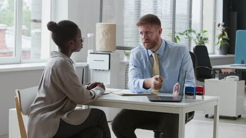Bank Clerk Giving Consultation to Female Client Getting Credit Card in Office