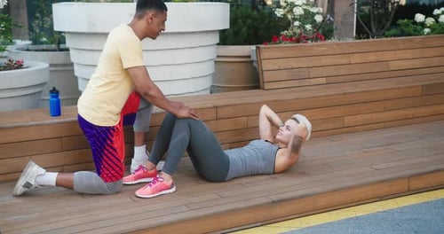 Woman Doing Situps with Trainer in Urban Setting