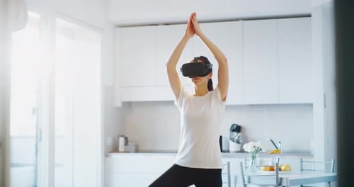 Woman Practicing Yoga Using VR Headset at Home