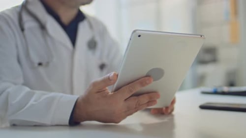 Hand of Anonymous Physician Using Tablet while Consulting Patient in Clinic