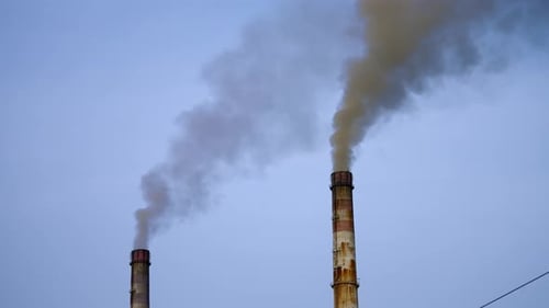 Smoke pouring from two industrial pipes. Factory cocncrete pipes pollute air with smoke.