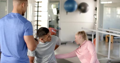 In disability rehab, therapist assisting man with back pain during physical therapy