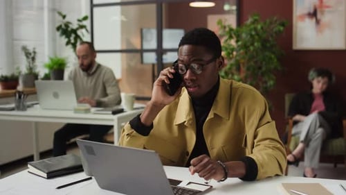 Young Adult Working in Office with Laptop and Phone