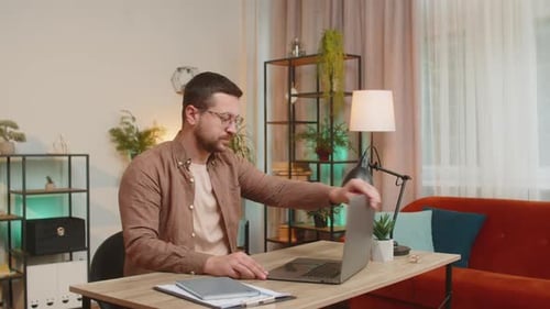 Caucasian Young Businessman Opening Laptop and Working on Project Sitting at Home Office Table Desk