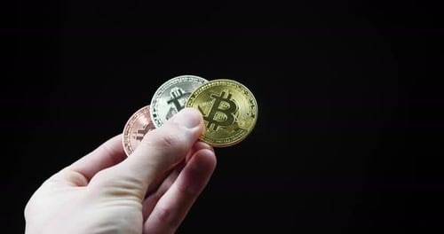 Hand holding Bitcoin golden coins, cryptocurrency assets, digital money concept in studio with black