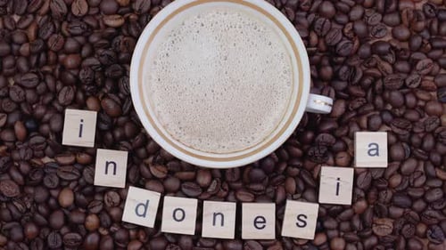 Cup with Coffee on a Background of Coffee Beans with the Word Indonesia Outlined