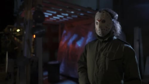 Man in the Old Hockey Mask Standing in the Warehouse and Holding a Chainsaw Looking at the Camera