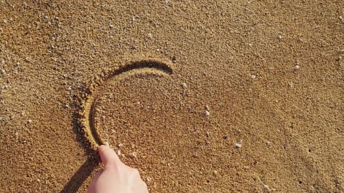 Woman Drawing a Sign of Peace in the Sand on a Sunny Beach