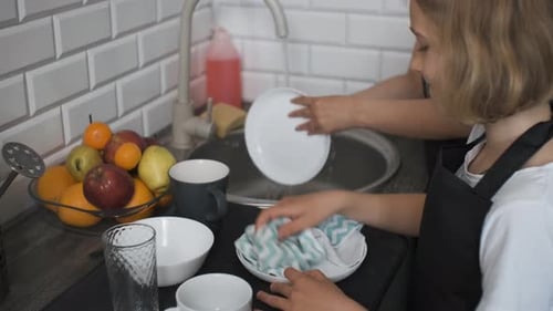 Child and Adult Washing Dishes in Kitchen