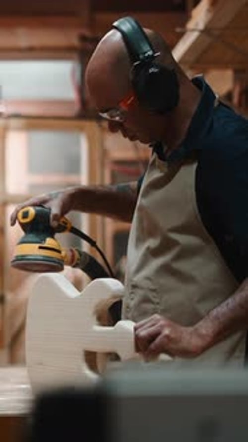 Professional Luthier Crafting and Sanding Electric Guitar Body in His Workshop