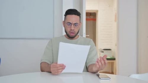 Man Reacting to Paperwork With Surprise Indoors