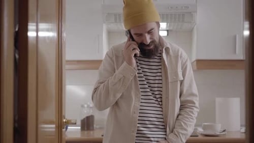 Smiling Man Answers Phone Call in Kitchen