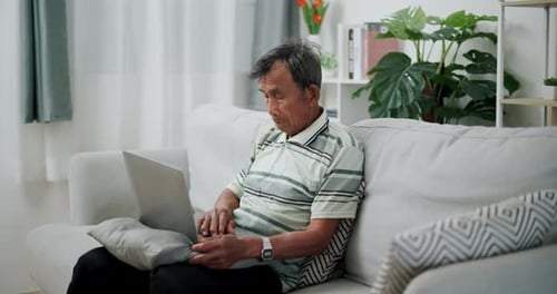 Senior Man Using Laptop on Couch at Home