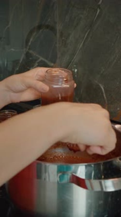 Woman Filling Jar with Homemade Sauce in Kitchen