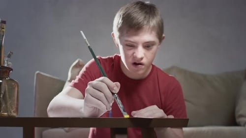 Boy Painting with Yellow Paintbrush Indoors