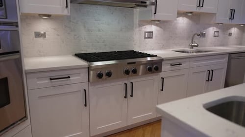 Modern white kitchen interior with large island and stain steel appliances. Modern kitchen in shaker