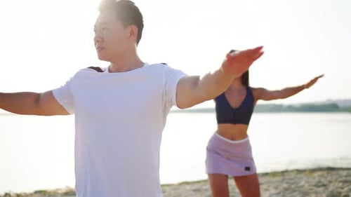 Side View Multiethnic Young Sportive Couple Doing Active Fitness Exercise Workout on the Beach