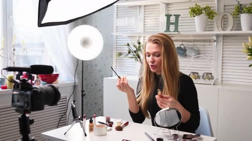 Mujer bloguera de belleza filmando un tutorial diario de rutina de maquillaje ante la cámara, la influencer Blonde Lady Live