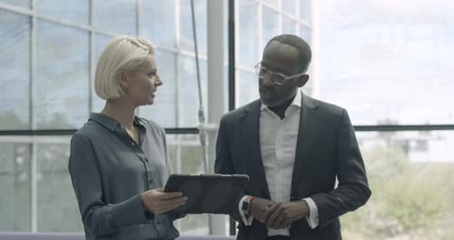 Business people in office meeting in lobby and discussing presentation on digital tablet