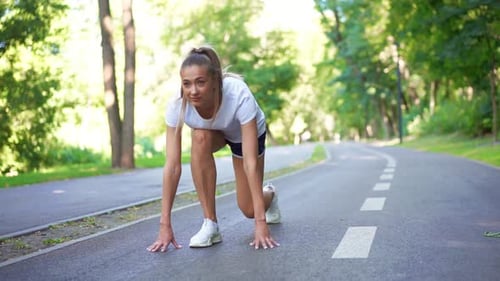 Sporty Woman Runner Starting Run From Low Start in Park