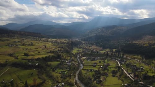 Sun Rays Break Through the Clouds Over Ukrainian Village Aerial View of Scenic Carpathian Landscape