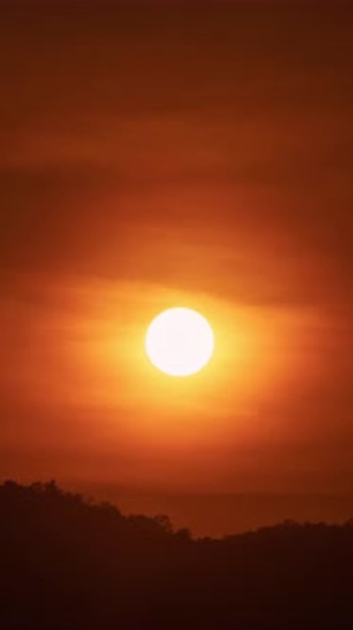 Zeitraffer eines dramatisch Sonnenuntergangs mit orangefarbenem Himmel an einem sonnigen Tag.