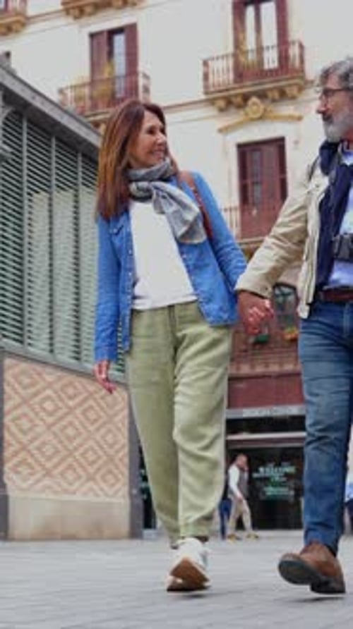 Happy Senior Couple Laughing While Enjoying a Walk in Barcelona During Vacation