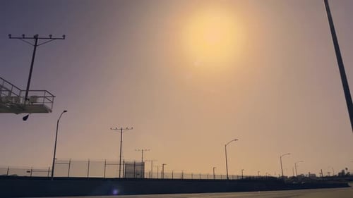 Low angle shot of a Jet airliner flying over a road before landing on the adjacent airport on a sunn