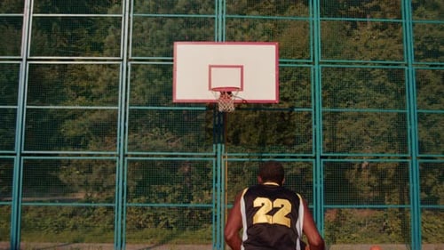Back Shot of African American Male Basketball Player Looking at Hoop and Throwing Ball Outdoor