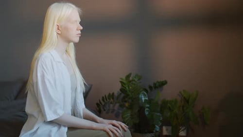 Blonde Haired Young Adult Sitting Calmly on Bed