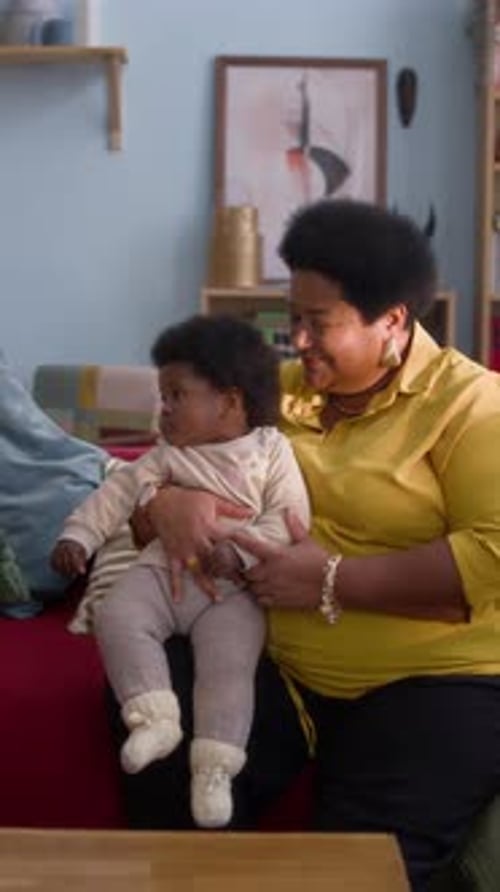 Woman Holding Baby Indoors, Smiling