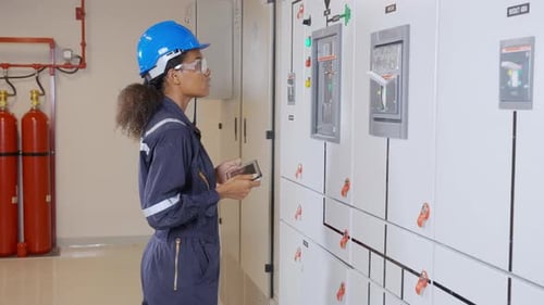 Female Electrical Engineer Adjusting Power Panel with Tablet