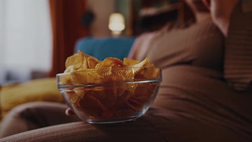 Woman Eating Chips While Sitting on Sofa