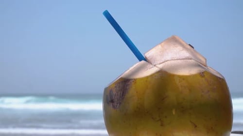 Frisches Kokosnussgetränk mit blauem Stroh am Strand mit Meereshintergrund