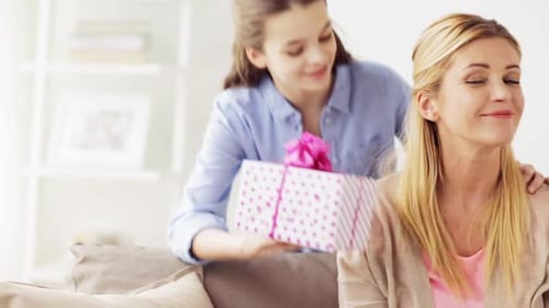 Smiling girl gives pretty present to happy woman