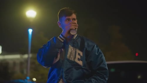 Man Pauses Next to His Stationary Car Under City Lights at Night Man Halts Beside His Immobile
