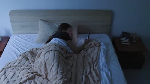 Woman Using Mobile Phone in Bed at Night Facing Sleeplessness