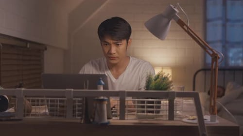 C5425Asian young man overworking while his wife sleeping in bedroom at night.
