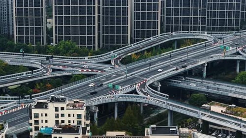 Aerial View of Cars and Trucks Travel Along a Network of Elevated Highways and Overpasses Buildings