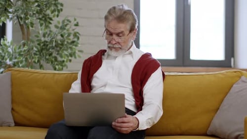 Senior Man Using Laptop on Sofa