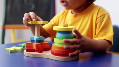 Child Builds Colorful Stacking Tower at Table