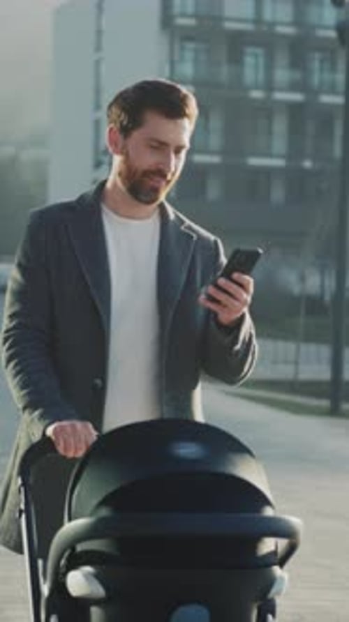 Man Pushing Stroller While Checking Messages Dad Navigating City Street with Baby Stroller and