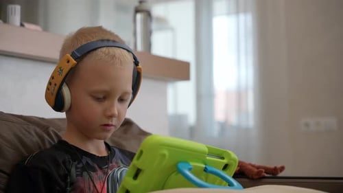 A young fair-hair boy studying remotely using a tablet.