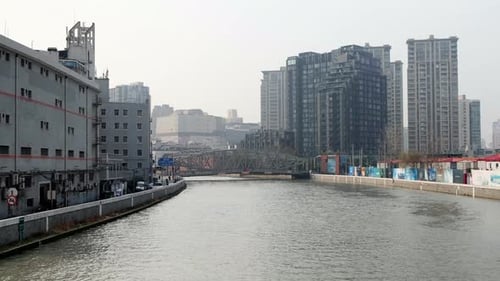 Urban canal lined with modern high-rise buildings and industrial structures in Shanghai, China on a