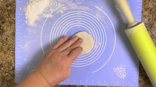 Rolling out round pieces of raw dough with a rolling pin to make patties. Top view.